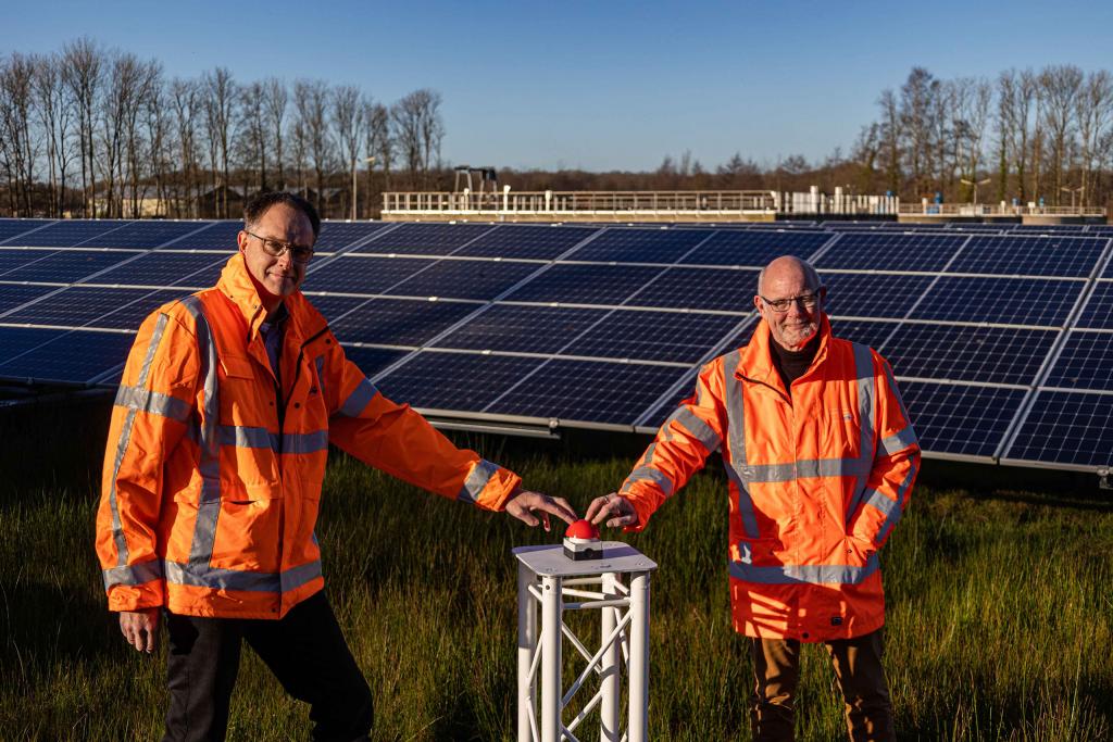 Dagelijks bestuurslid Herman Beerda en adviseur duurzaamheid Tjitse Mollema van waterschap Noorderzijlvest nemen bij de zuiveringsinstallatie in Eelde de zonneparken symbolisch in bedrijf. 